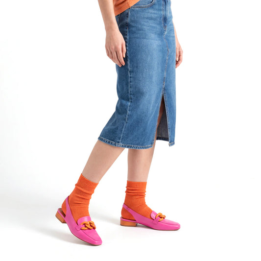 Person wearing a blue denim skirt, orange socks, and pink shoes on a white background