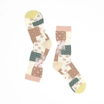 A pair of knee-high socks with a patchwork design featuring floral prints, polka dots, and solid color blocks in beige, brown, green, pink, and yellow on a white background.