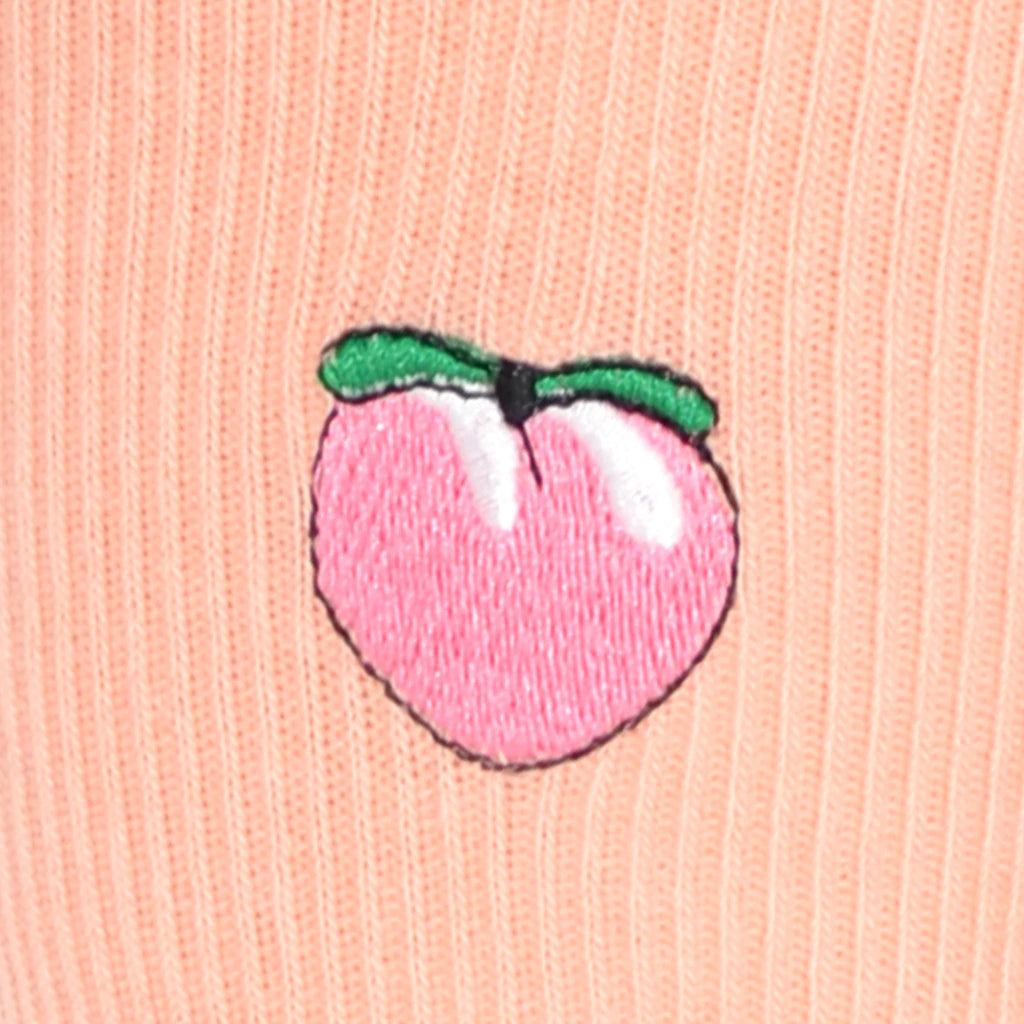 Embroidered peach design on a pink fabric background