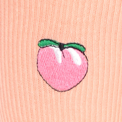 Embroidered peach design on a pink fabric background
