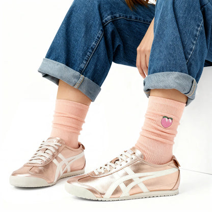 Person wearing pink socks with a heart design and white sneakers on a white background