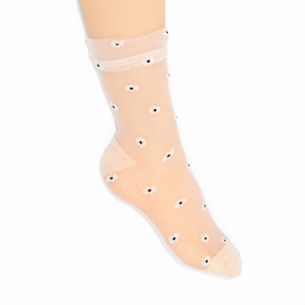 A single ankle sock worn on a foot, made of sheer peach-colored mesh with small white daisy patterns and black centers, set against a plain white background.
