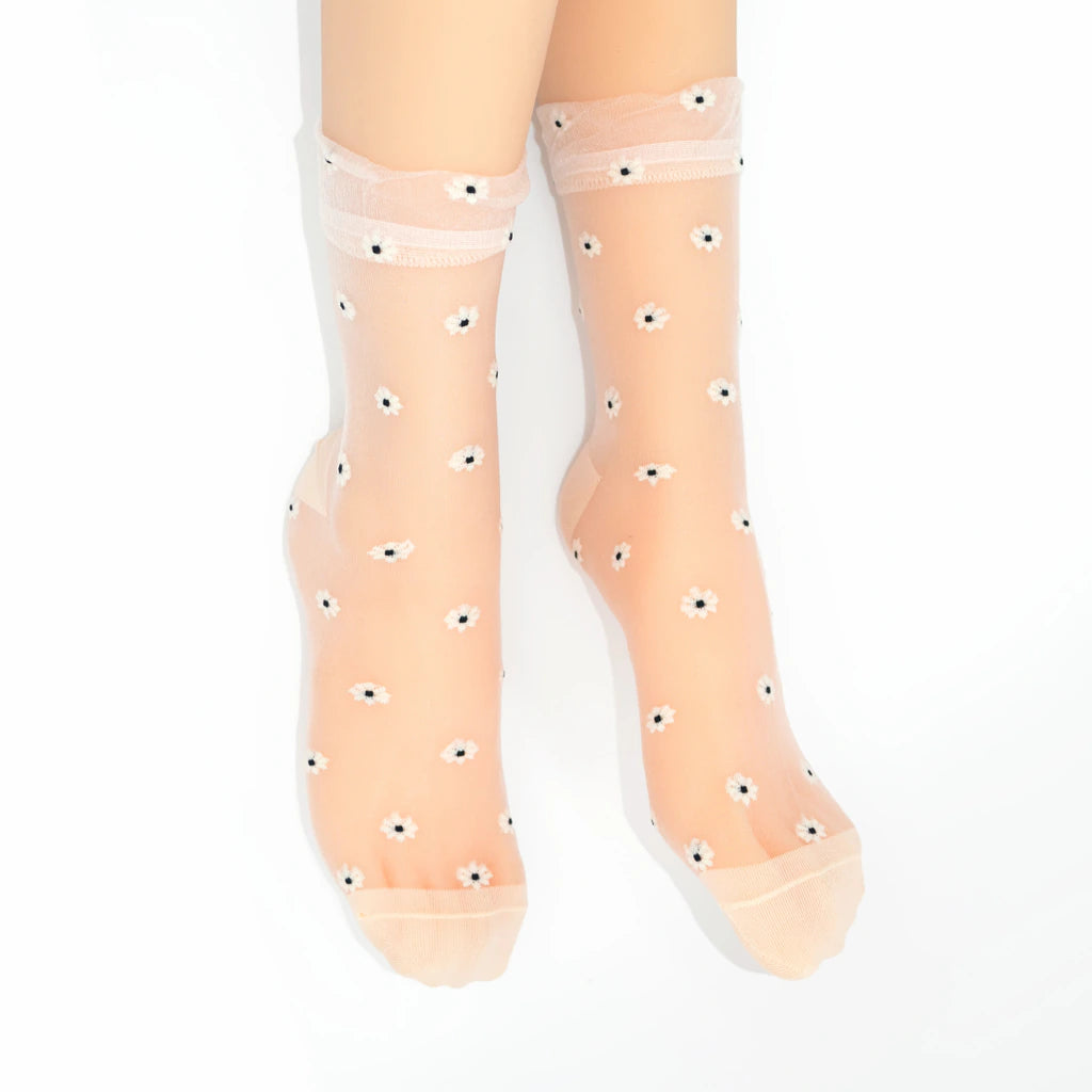 A pair of sheer nude tulle socks with small white and black eye motifs, shown on a model's feet against a white background.