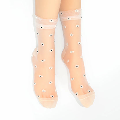 A pair of sheer nude tulle socks with small white and black eye motifs, shown on a model's feet against a white background.