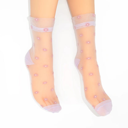 A pair of sheer light pink ankle socks with small pink floral patterns and solid pink toe, heel, and cuff sections, shown on  feet against a white background.