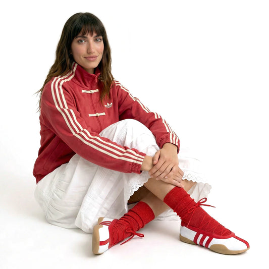 Person wearing a red Adidas tracksuit with white stripes on a white background