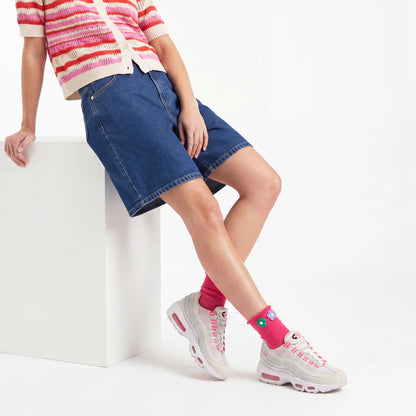 Person wearing a striped sweater, denim shorts, and pink sneakers on a white background