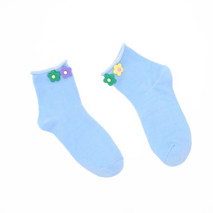 Pair of light blue socks with colorful flower decorations on a white background