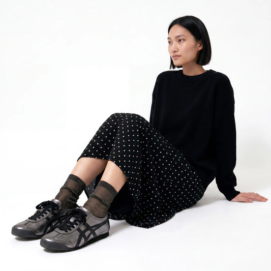 Model wearing Tiffany Black Diamond sheer sparkle socks with black trainers and a black polka dot skirt.