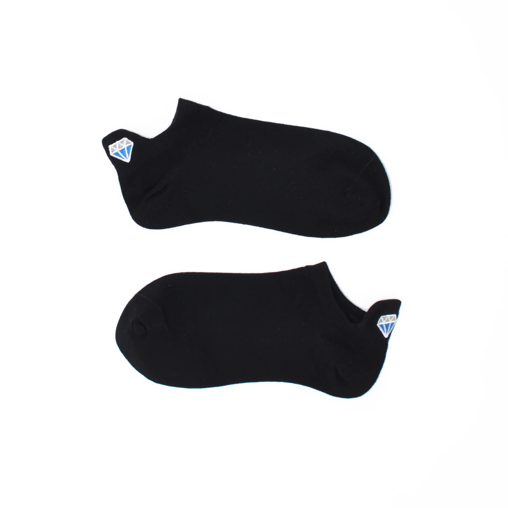 A pair of black no show socks with diamond-shaped embroidered tabs at the heel.