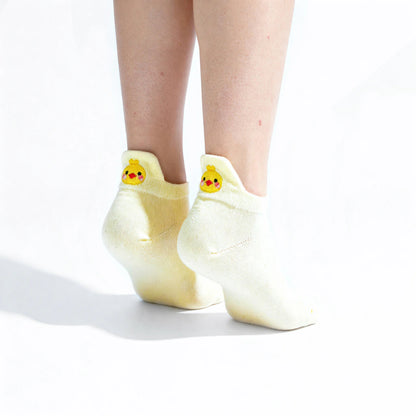 Soft yellow socks with chicken embroidered motif design worn by a person on a white background