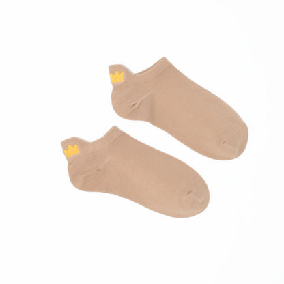 A pair of beige no-show socks with an embroidered tab at the heel