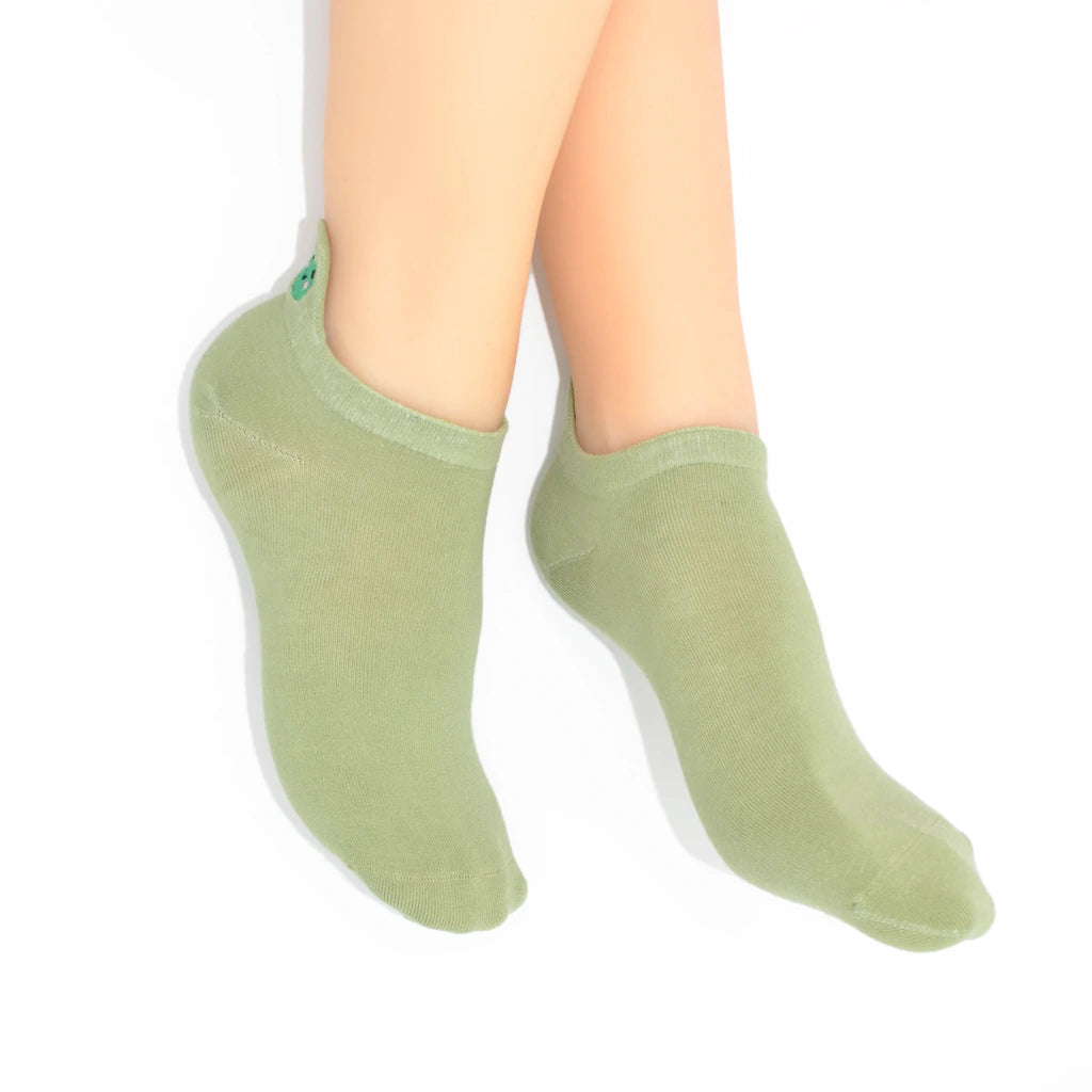 Legs modelling sage green no-show socks with an embroidered frog heel tab.