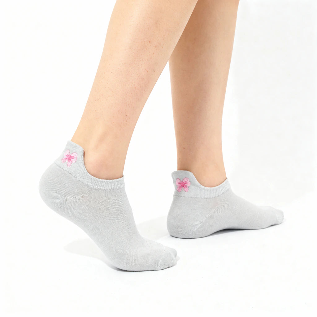 Gray ankle socks with a pink bow worn by a person on a white background