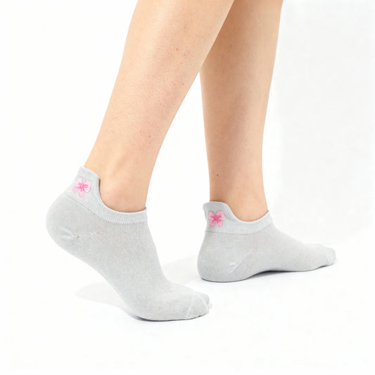 Gray ankle socks with a pink bow worn by a person on a white background
