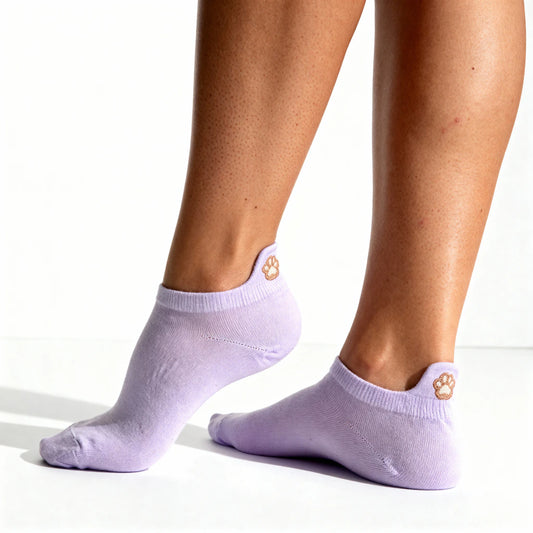 Purple ankle socks with paw print design worn by a person on a white background