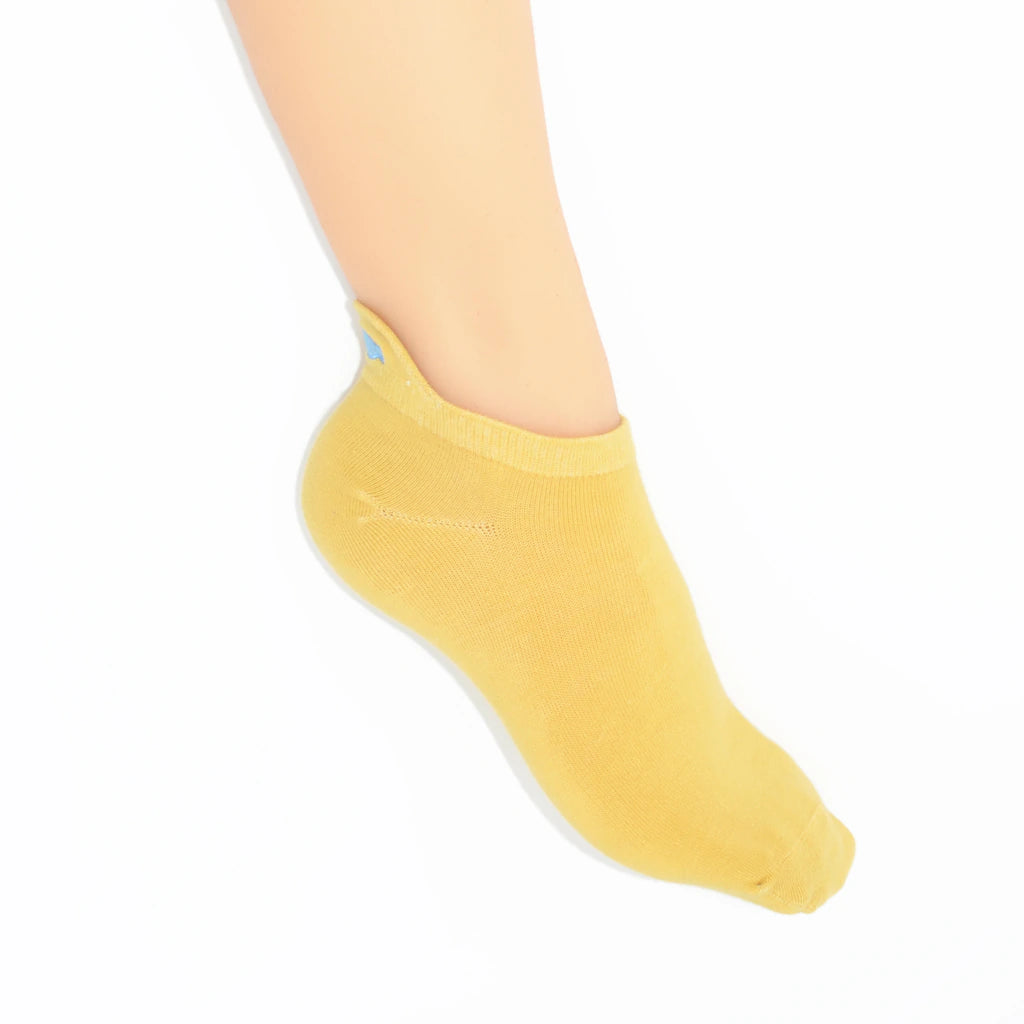 A leg modelling  yellow no-show socks with an embroidered fish heel tab.