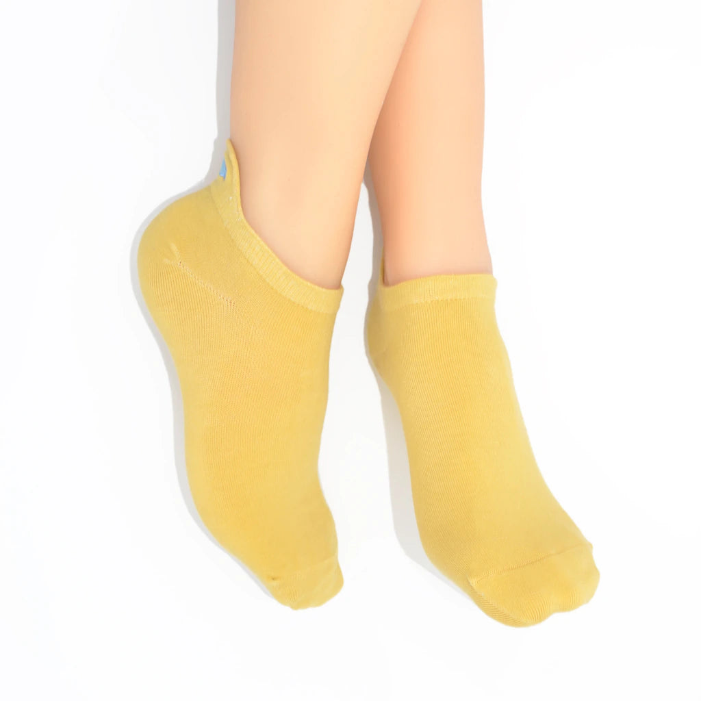 Legs modelling  yellow no-show socks with an embroidered fish heel tab.