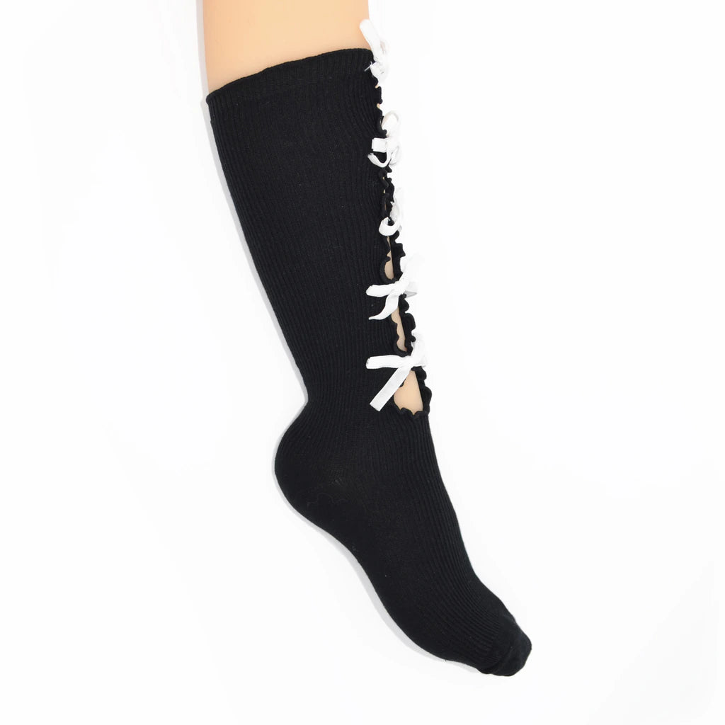 A black ribbed knee-high sock with white lace-up detailing running down the side, shown on a leg against a plain white background.