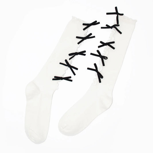 A pair of white thigh-high socks with black lace-up bow details running up the front, displayed on a clean white background.