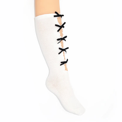 A white ribbed knee-high sock with black lace-up details down the front, shown on a leg against a plain white background.
