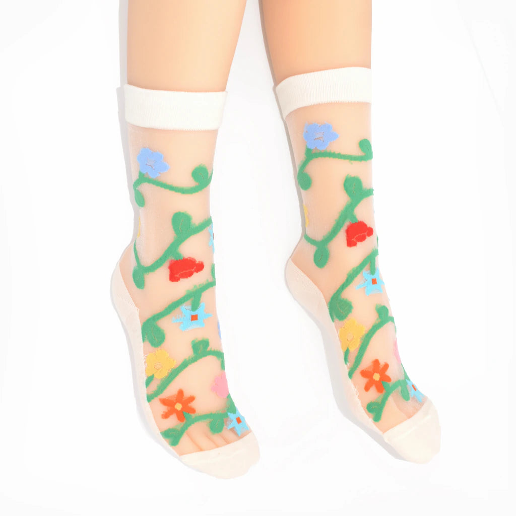 Sheer socks with colorful floral patterns worn by a person on a white background