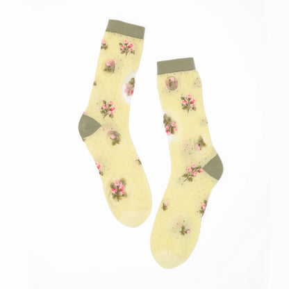 A pair of sheer yellow ankle socks with a pink floral print and olive green trim, displayed against a solid white background.