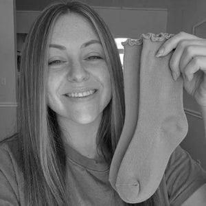 Jen holding a pair of socks in a black and white photo
