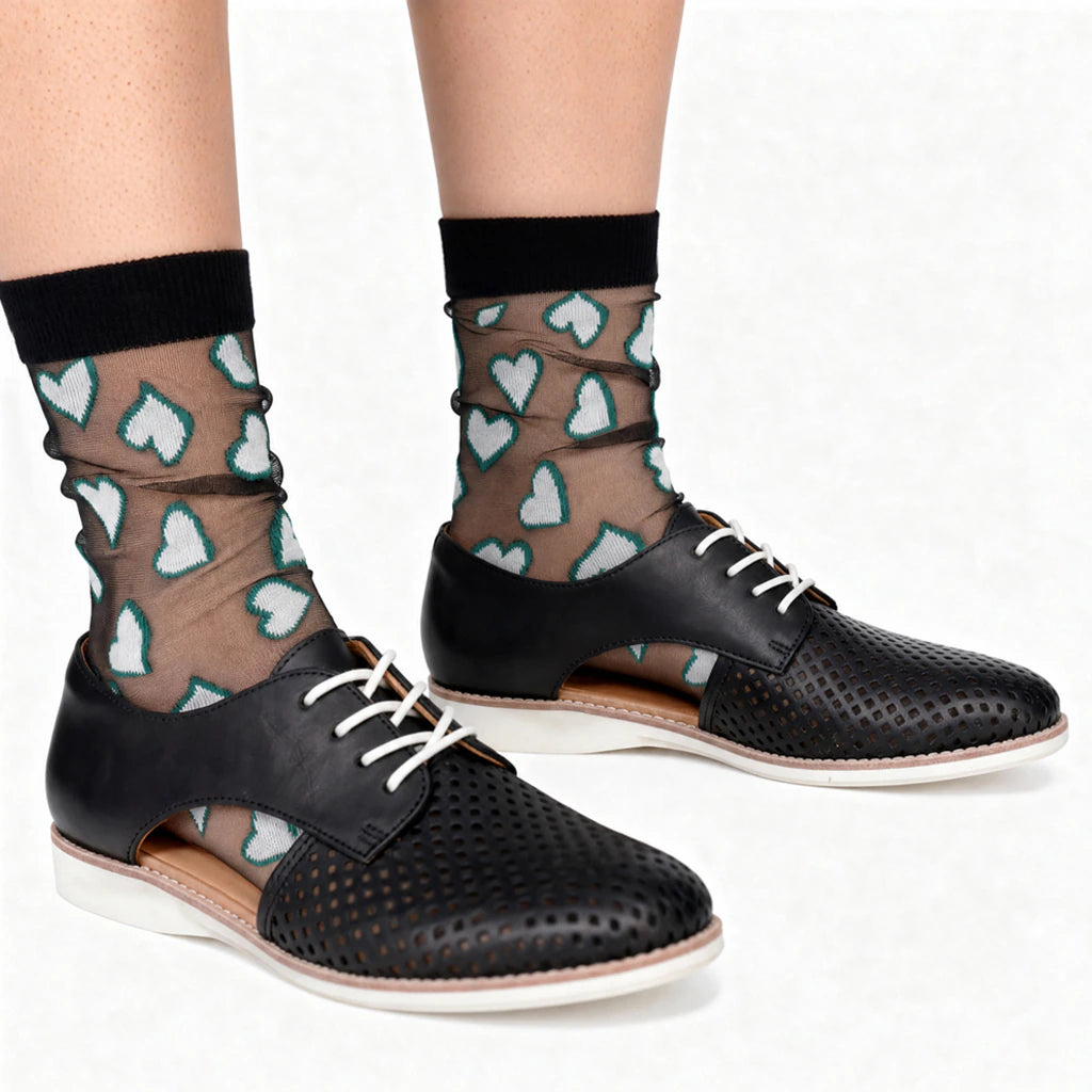 Black shoes with white laces worn with sheer socks featuring heart patterns on a white background