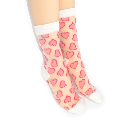 Sheer socks with pink heart pattern worn by a person on a white background