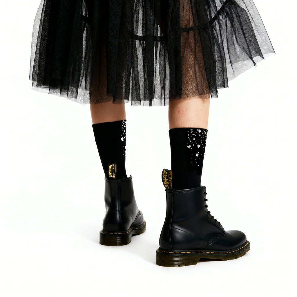 Black tulle skirt, black socks with gold accents, and black boots on a white background