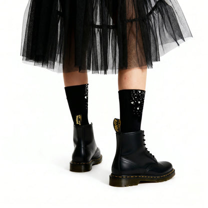 Black tulle skirt, black socks with gold accents, and black boots on a white background