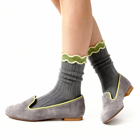 Gray socks with green trim worn with gray flats on a white background