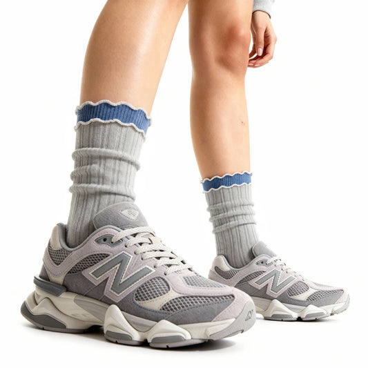 Gray New Balance sneakers with blue accents worn with gray socks on a white background