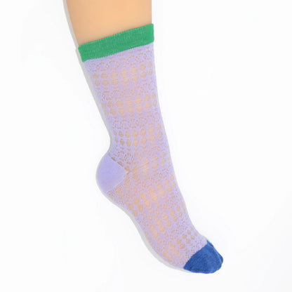 A leg modelling light purple socks with green cuffs and blue toes on a white background