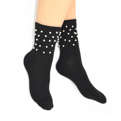 Black socks with white pearls worn by a person on a white background