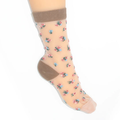 A single ankle sock shown on a  foot against a plain white background. The sock is sheer nude beige with a small scattered floral print in pink, blue, and green, plus solid brown heel and toe sections.