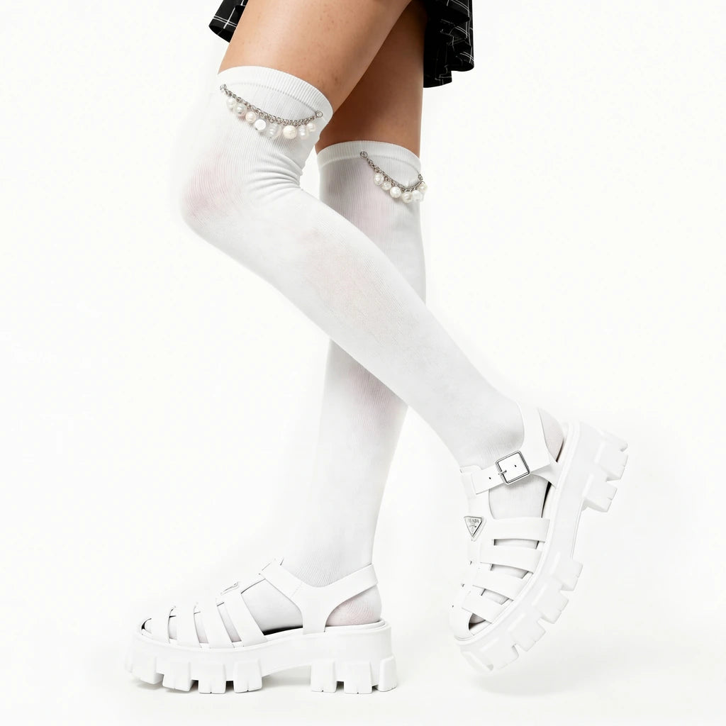 White knee-high socks with pearl details worn with white sandals on a white background