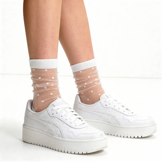 White sneakers with sheer socks featuring polka dots on a white background